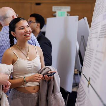 student looks at poster at event