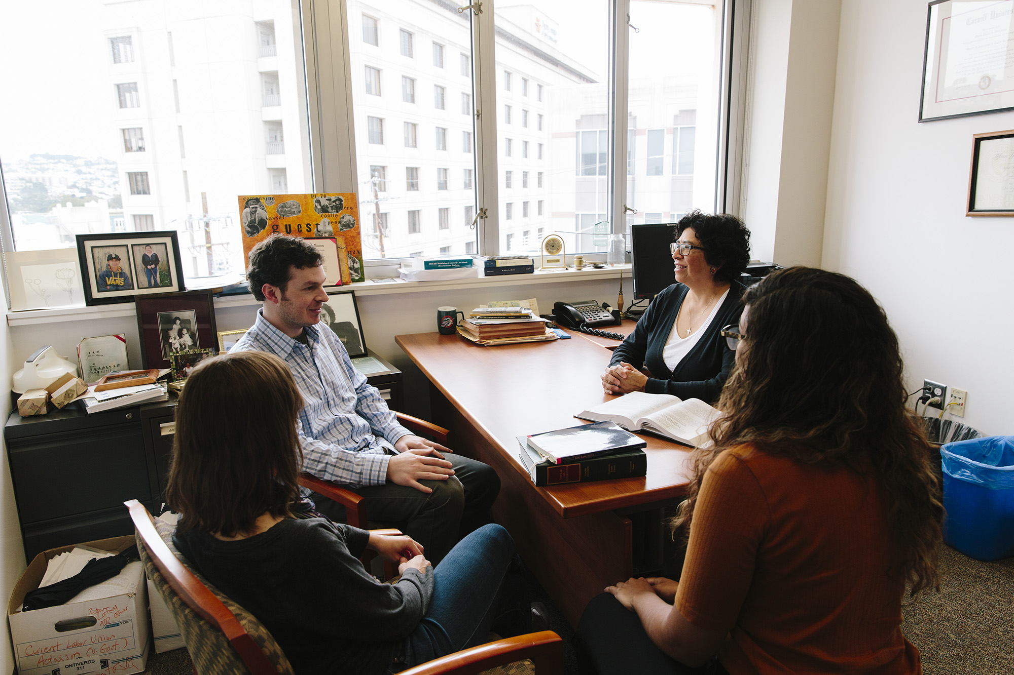Professor Maria Ontiveros and three students sitting around her desk