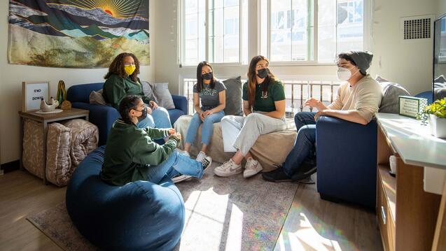 Several students chat in a dorm room.