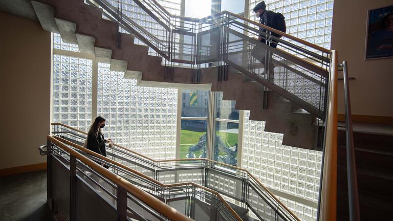 Students walk the stairs in Gleeson Library.