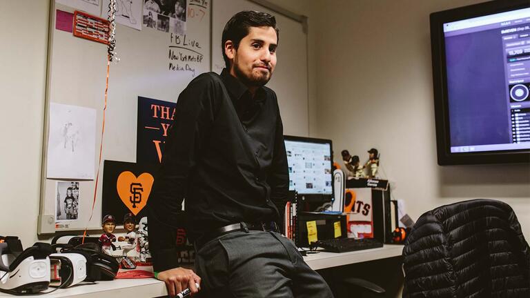 Alfonso Garcia sits on a desk in the office.