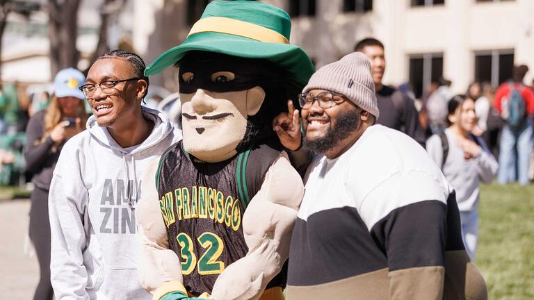 Two students strike a pose with the Dons Mascot