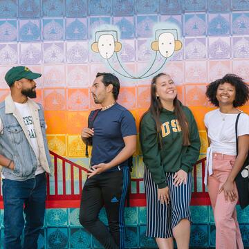 Students chat in front of a mural of the Golden Gate Bridge.