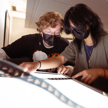 Film students inspect a strip of film at a light table.