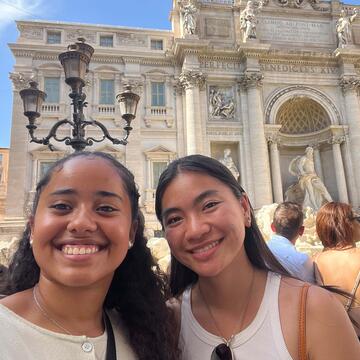 Two students pose in front of an ancient Roman building.