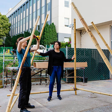 two students building with bamboo