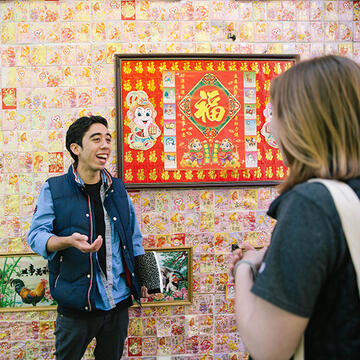 student standing in front of a colorful wall in Chinatown San Francisco