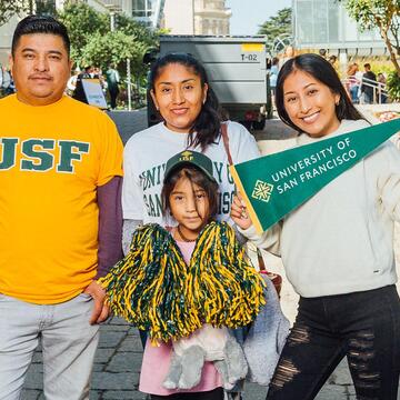 A family poses together at Orientation with USF gear and pom poms