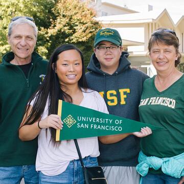 Family members with a student hold USF banners and foam fingers.