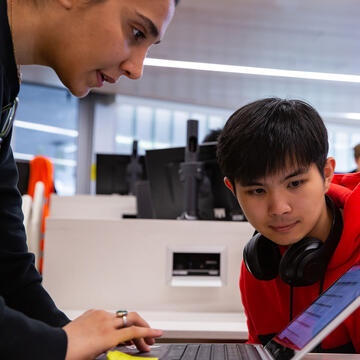 Two students look at a laptop in class