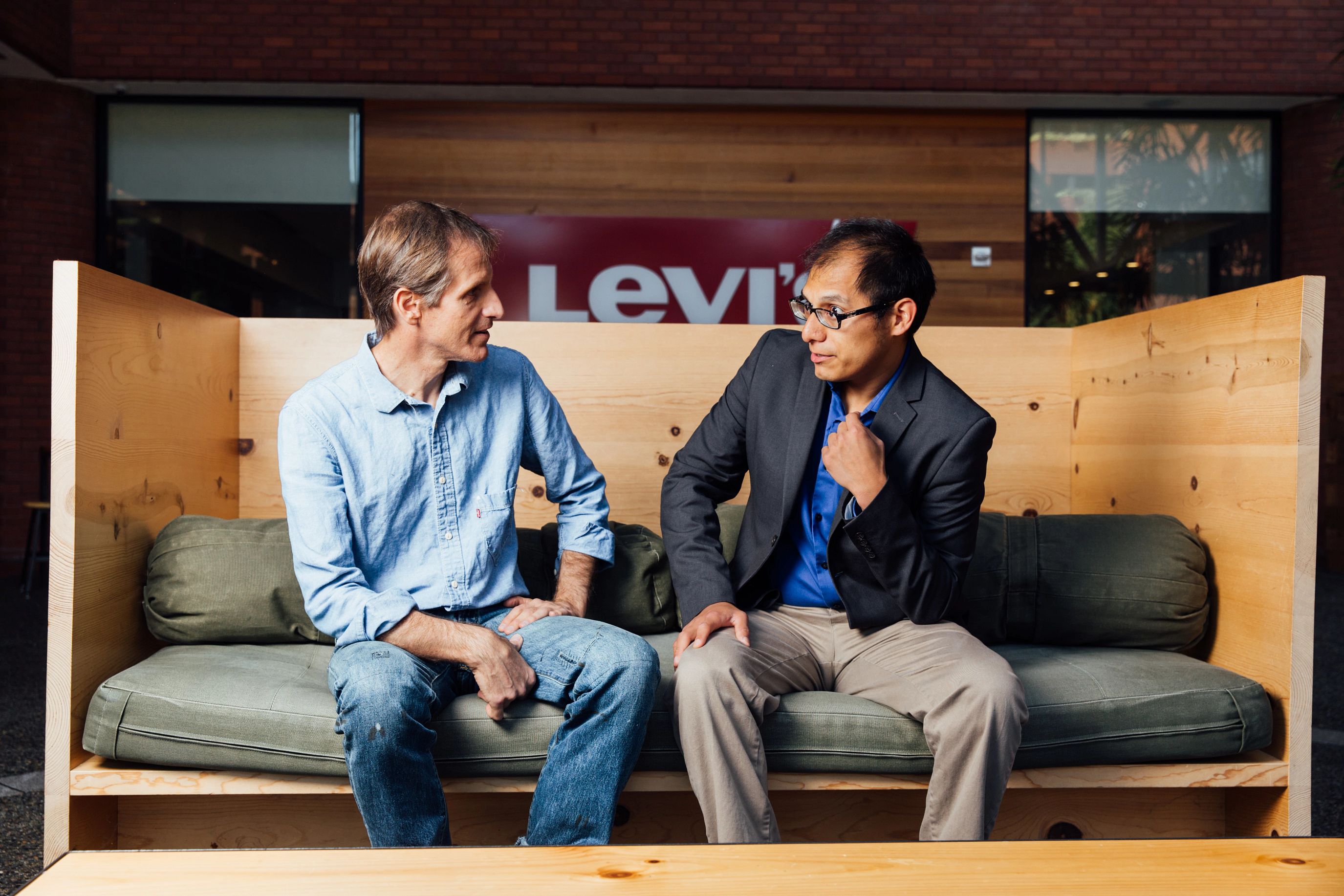 Two people sit on a bench and discuss