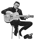 Johnny Cash holds a guitar while sitting