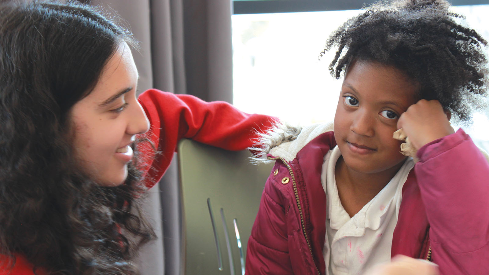 A student sits with a young person in a classroom