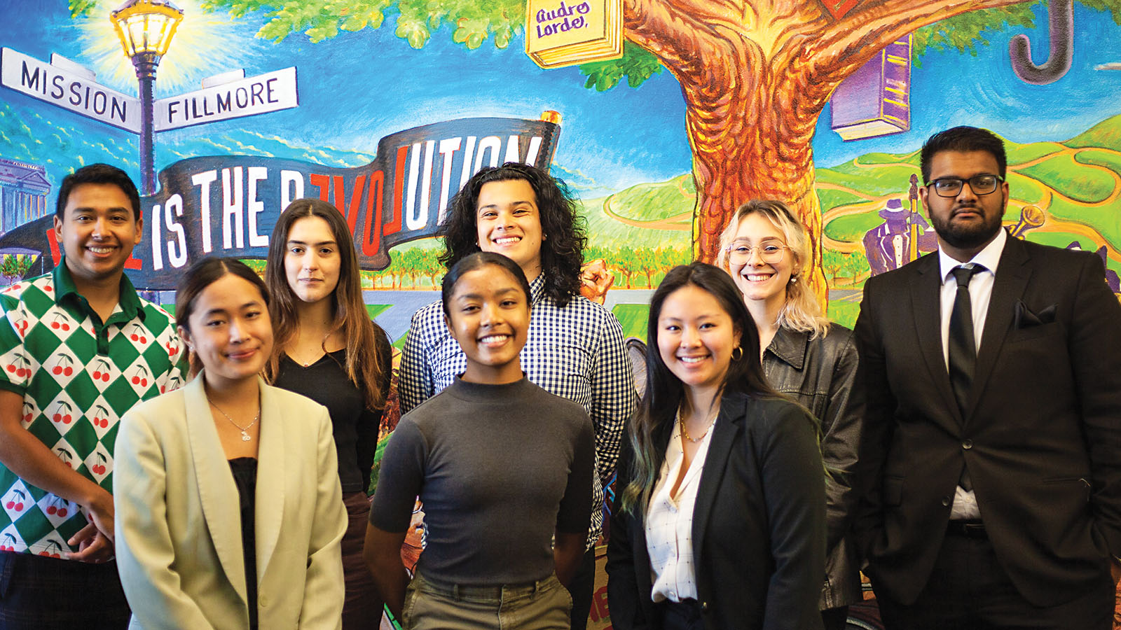 Fellows pose for a photo in front of a mural in center's office
