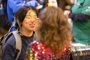 Student has USF colors painted on their forehead by face-painting artist.