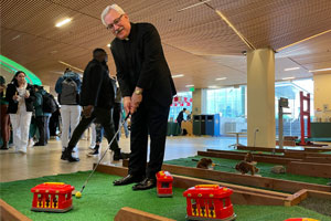 Fr. Fitzgibbons plays a round of mini golf on a cable car trolley course.