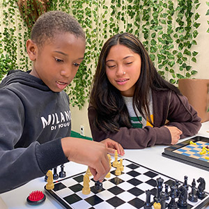 student plays chess with youth