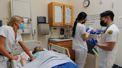 Three nursing students practicing on a fake patient