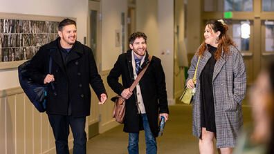 Three USF students walking in a hallway and chatting