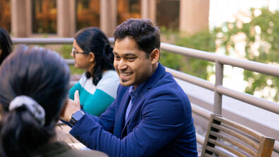 student sitting at a table outside smiling