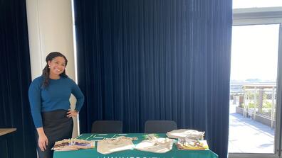 Kelsey Green in front of a table that says "University of San Francisco, School of Nursing and Health Professions"