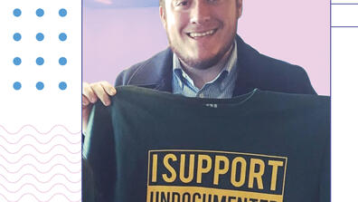 Flavio Bravo holding shirt that says "I support undocumented students"