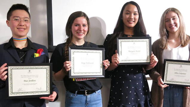 Four students holding diplomas