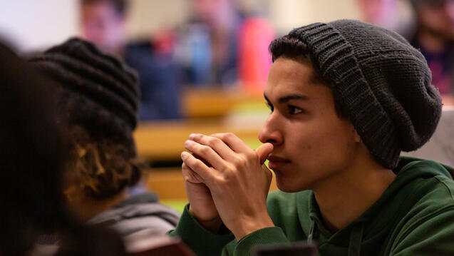 Student with a knit cap on listens in class.