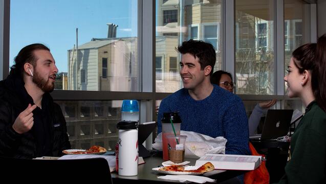Students talk during a study group at a large table.