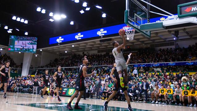 USF basketball game with a player dunking in foreground.