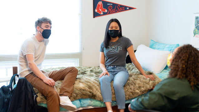 Students chat in a dorm room.
