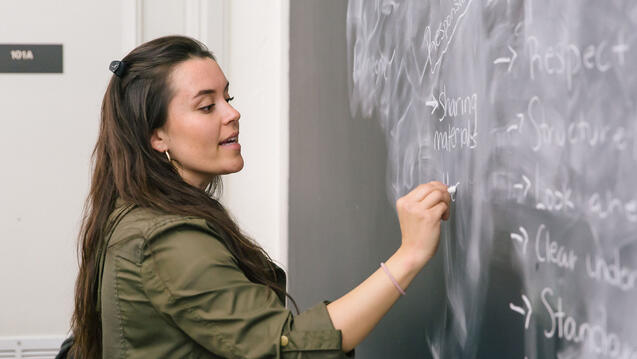 Person writing on chalkboard.