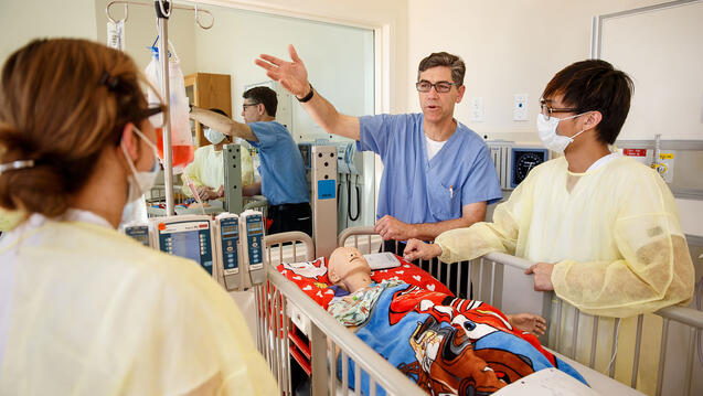 professor gestures to nursing students in immersive learning space