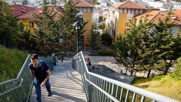 Student walking up stairs with view of Loyola Village in the background