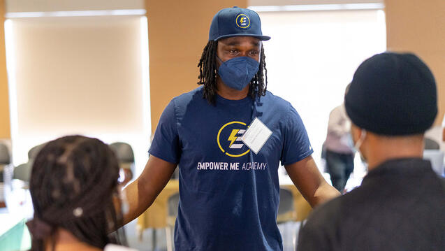 Staff member speaks with students at event.