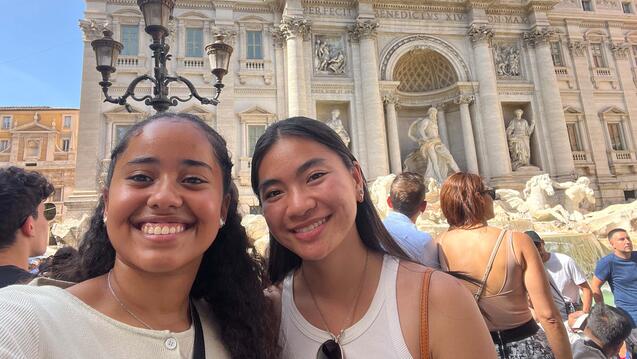 Two students pose in front of an ancient Roman building.