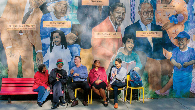 Professors, community members, and a student in front of a Western Addition mural