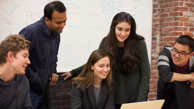 Students sitting at a table with their laptops.