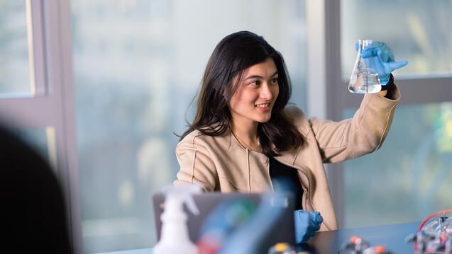 student examines a lab beaker