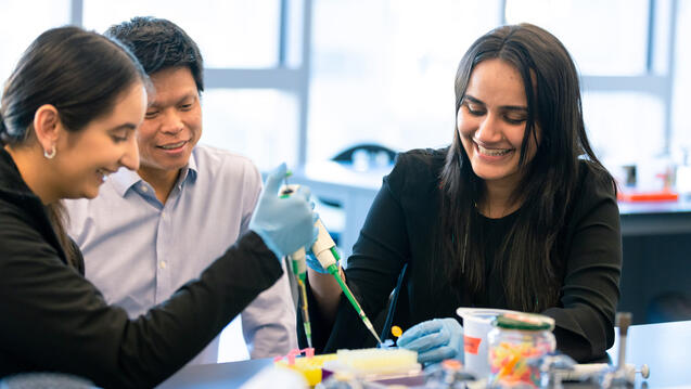 professor works with two students during lab work