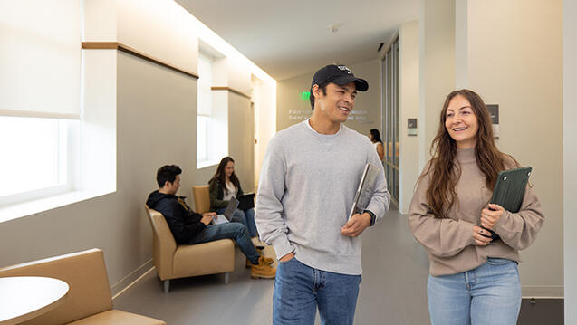 two students walking together inside the Orange County Campus building