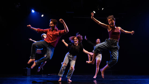 students in a mid-air jump during a dance performance