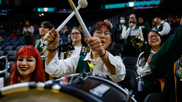 usf band member raising drumsticks in the air during basketball game