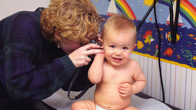 Pediatrician checking baby's ear with otoscope