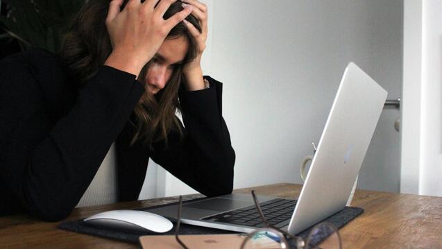 Stressed adult clutching her head in her hands