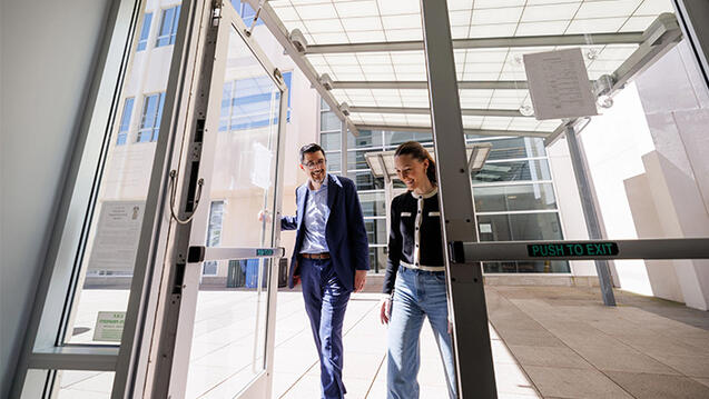 Professor and law student entering USF law building, smiling