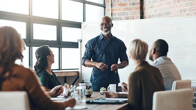 Business person presents to colleagues in a bright office with a whiteboard