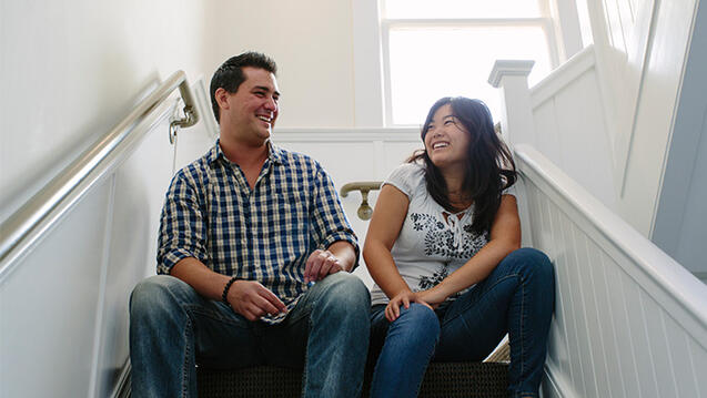 Two students in a stairwell chatting and smiling