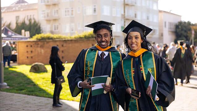Two people in caps and gowns after commencement