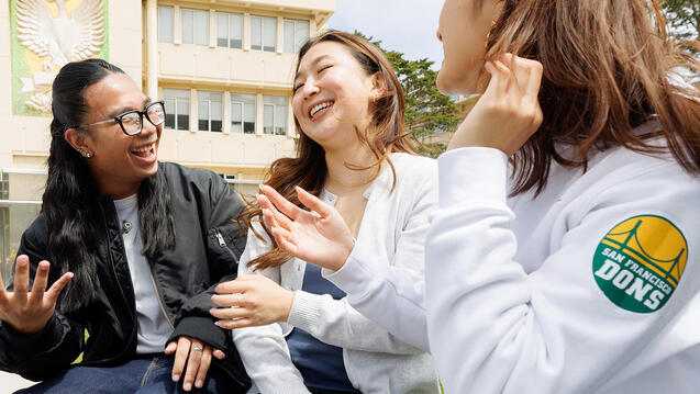 students laugh together outside on campus